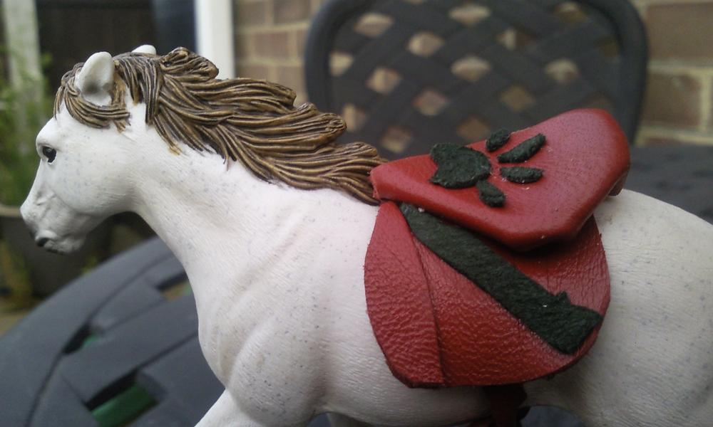 I made this out of scraps of red leather from another project i was working on and i decided to see what a saddle would look like with a design on.